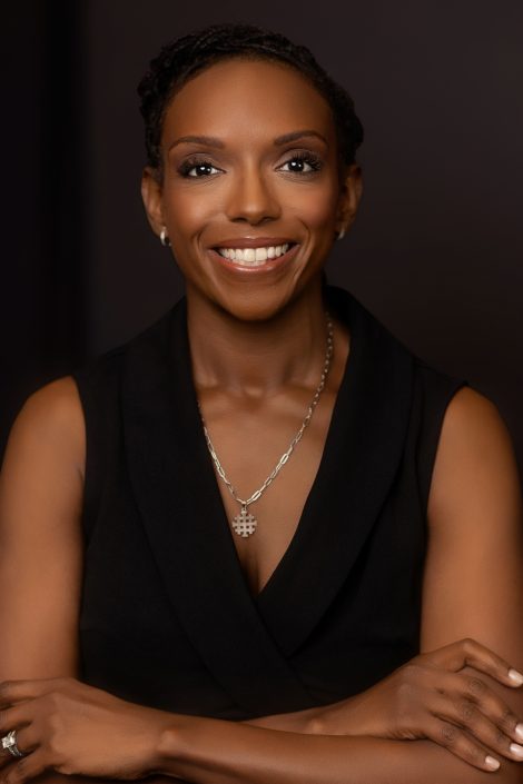 Professional headshot of Dr. CC Anthony smiling in a sleeveless black top against a dark background.