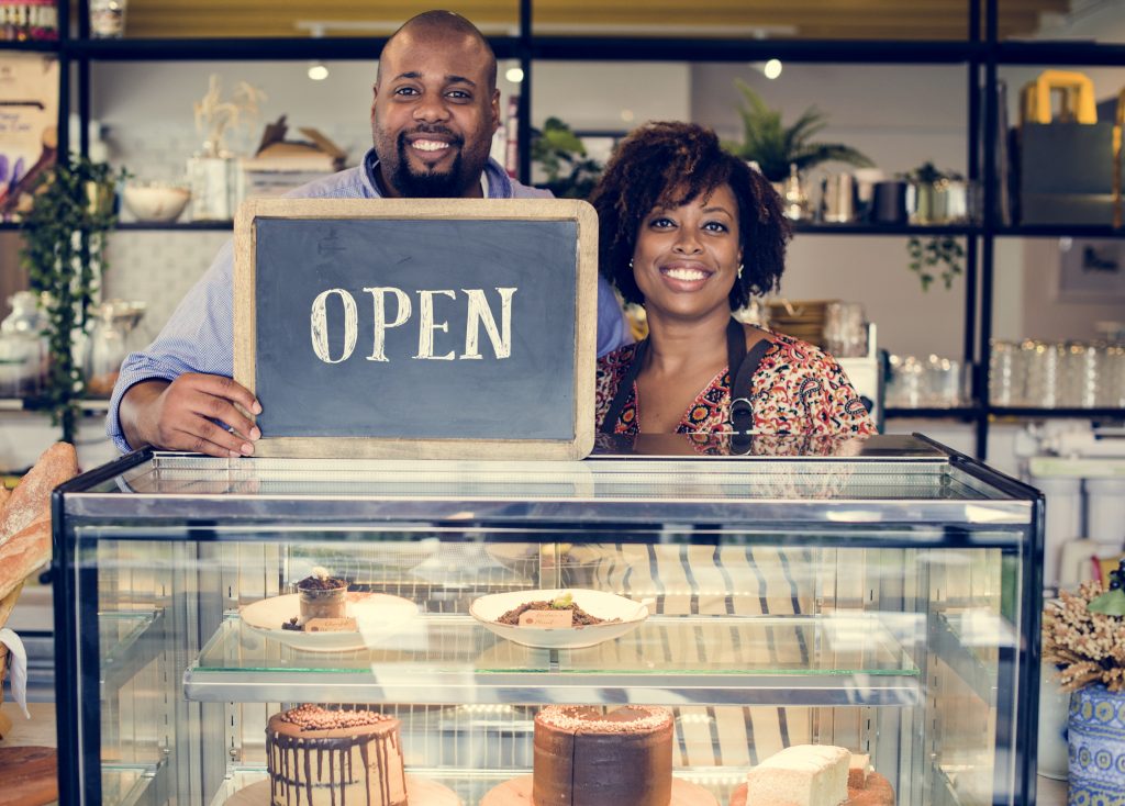 Small business owners standing inside their business representing entrepreneurship, business growth, and operational support services.